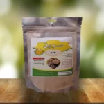 A clear plastic stand-up pouch of "سویق جو" powder, labeled in Persian with barley and biscuit images, sits on a wooden surface with a blurred green background—یک محصول از فروشگاه طب اسلامی.